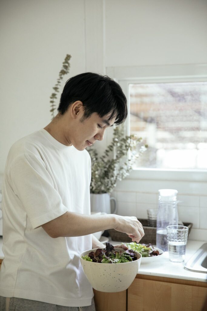 Asian man serving salad into plate