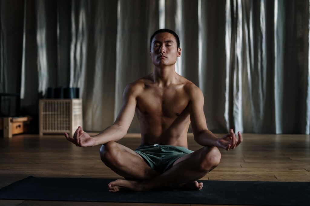 meditating Topless Man in Blue Denim Shorts Sitting on Floor