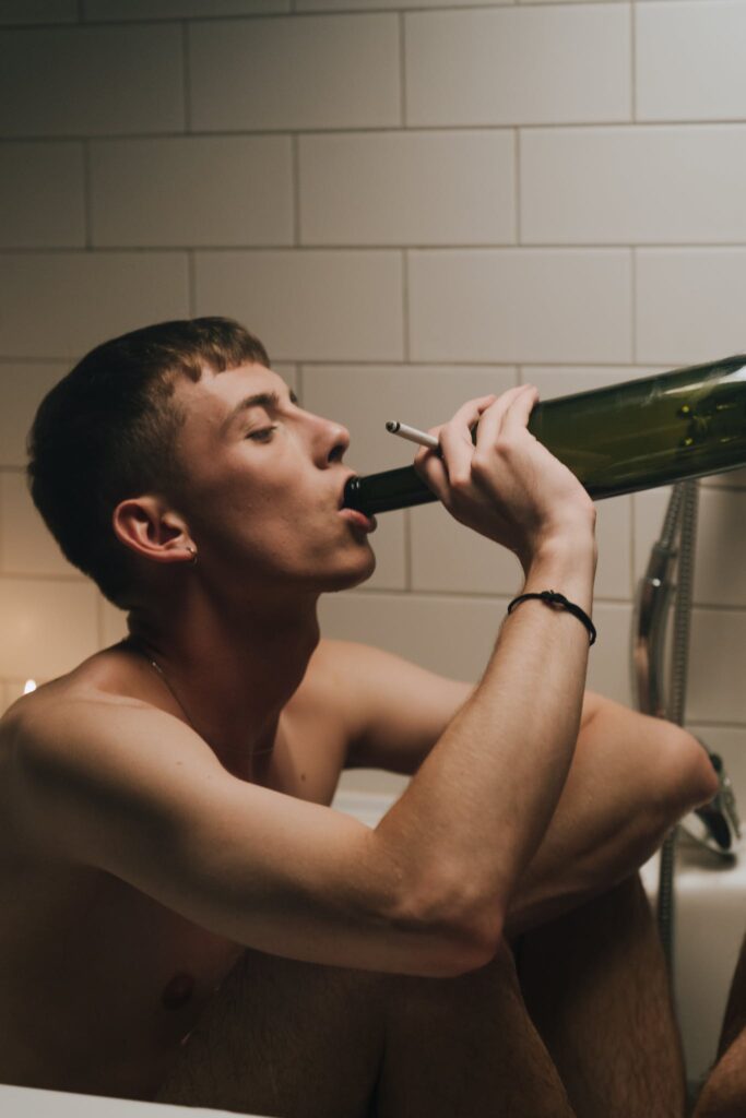 Topless Man Drinking from Wine Bottle